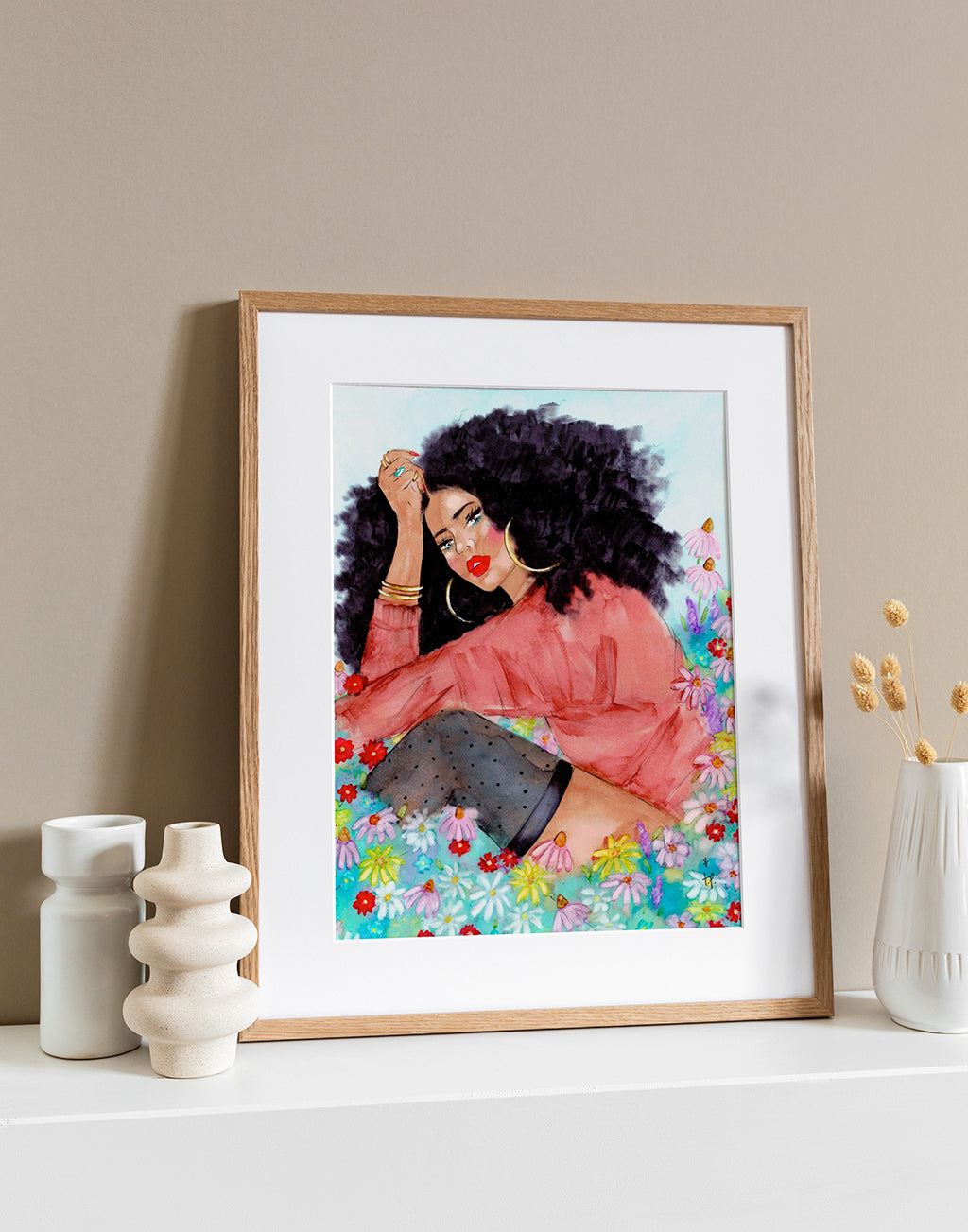 Illustration in a light frame of a beautiful woman with big natural hair sitting in field of wildflowers by Tatiana Poblah